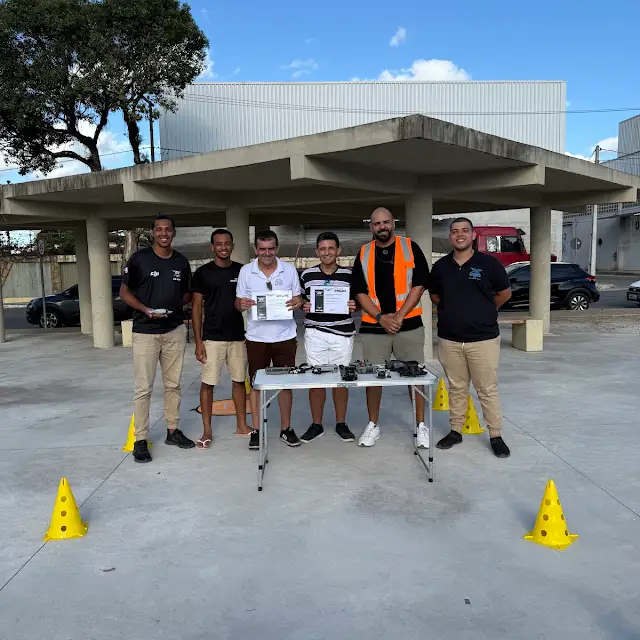 Alunos com certificados durante aula prática com cones e drones na pista