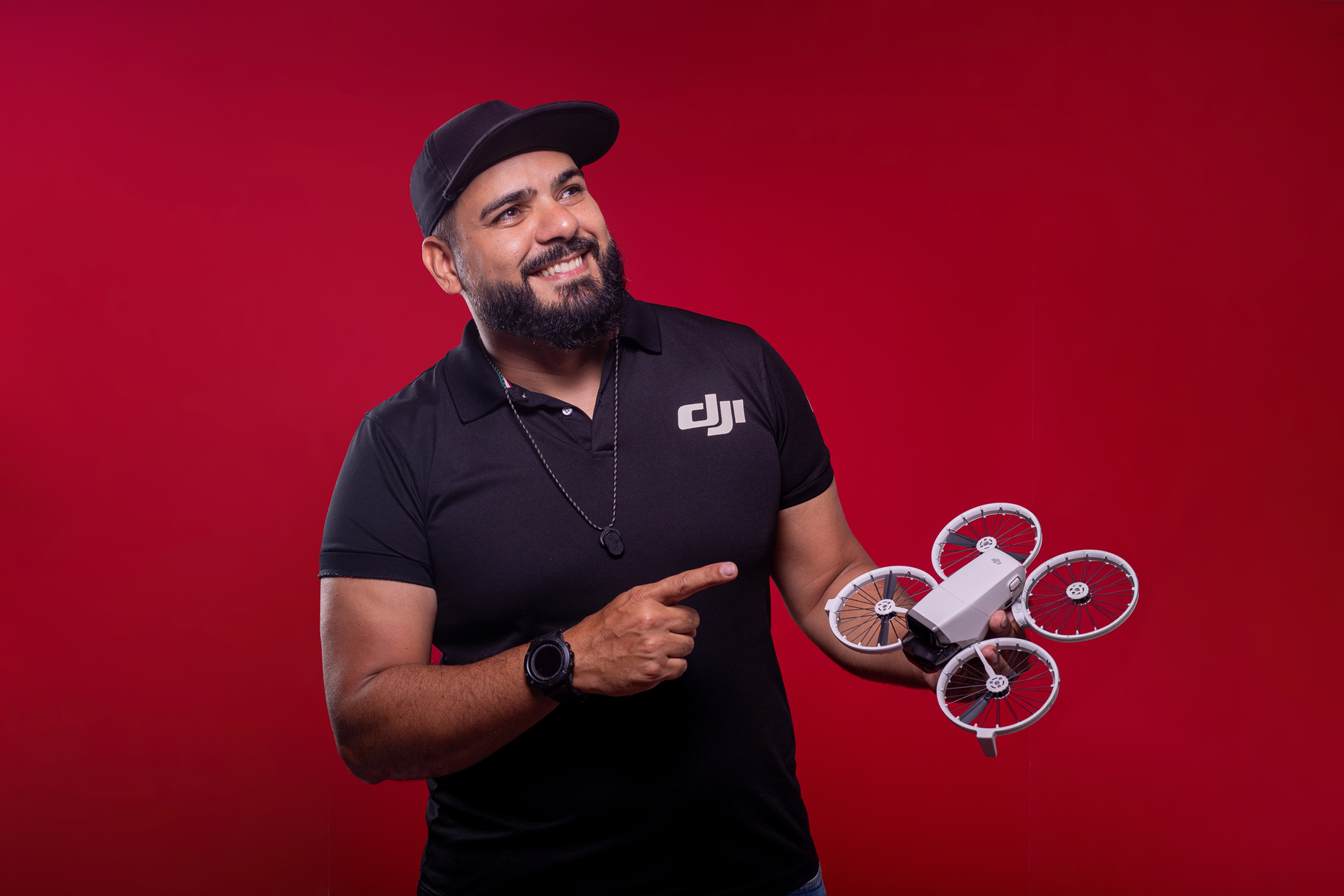 Zé Drone sorrindo e apontando para um drone DJI Neo